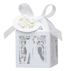 Détail de boîte cadeau blanche ajourée au laser avec motifs floraux et étiquette de merci
