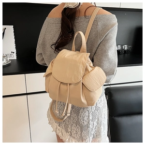 Detail view of beige nylon backpack with drawstring closure and stylish side pockets