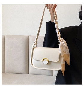 Détail du sac selle blanc cassé avec boucle dorée et bandoulière en chaîne de foulard