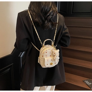 Detail eines Mini Rucksacks in Creme mit Bärenmuster und Goldkette am Rücken des Models