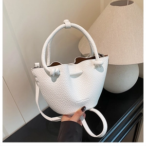 Close-up of white lychee pattern leather bucket bag with elegant wavy drawstring closure