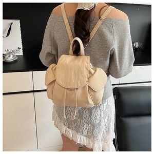 Detail view of stylish beige canvas backpack with drawstring closure and side pockets