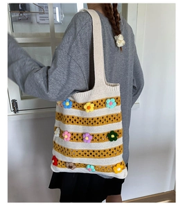Close-up of hand-knitted striped tote bag featuring 3D colorful crochet flower decorations