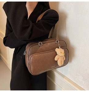 Detail of dark brown vintage Boston bag with plush bear charm and side shoulder view
