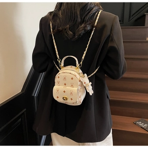 Mini-Rucksack in Creme mit Bärenprint, Goldschloss und Plüschhasen-Anhänger am Model
