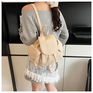 Detail view of the drawstring closure and magnetic flap on this light beige nylon backpack