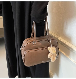 Detailed shot of large brown leather boston bag with bear charm and brand logo