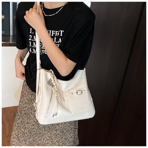 Detailed view of a white crocodile pattern tote bag with decorative tassel and metal zipper