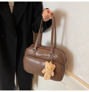 Detail of brown vintage Boston bag with plush bear charm and double zipper design