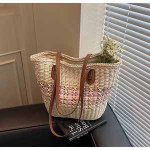 Détail du sac cabas en paille tressée avec lanières en cuir marron et motifs losanges
