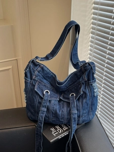 Vintage dark blue denim crossbody tote bag with pocket details on a black leather sofa