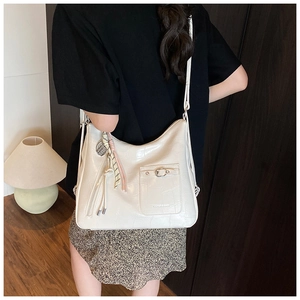 Close-up of beige crocodile-textured tote bag with silk scarf and tassel details