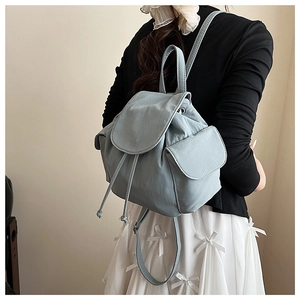 Close-up of light blue canvas backpack featuring drawstring closure and side buckle pockets