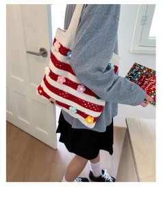 Détail du cabas en tricot à rayures rouges et blanches avec fleurs 3D au crochet