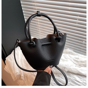Detail view of black lychee grain bucket bag with brand lettering and soft lace accents