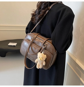 Detailed side view of brown faux leather boston bag with cute bear charm and zip pockets