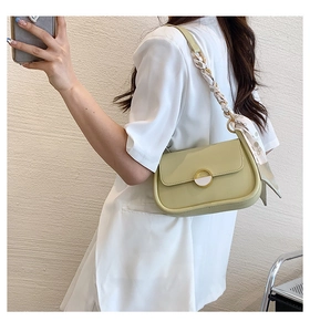 Détail du sac selle vert clair avec bandoulière en foulard de soie et boucle dorée