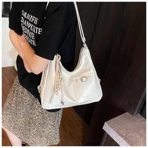 Detail view of large white crocodile pattern leather tote bag with tassel charm for women
