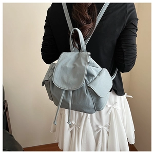 Rear view of a light blue canvas bucket backpack worn over a stylish white dress