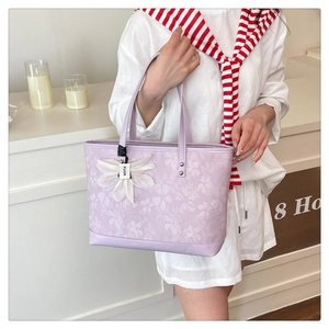 Close-up of a floral tote bag featuring a white 3D flower charm and purple pattern