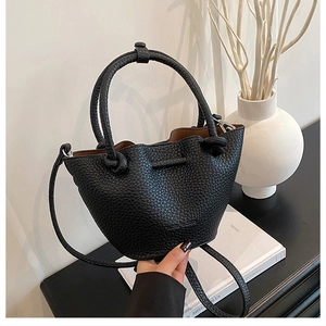 Detail of black lychee grain leather bucket bag with knotted handles and thin strap
