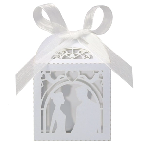 Detail of white laser-cut wedding favor box with ribbon bow and couple silhouette