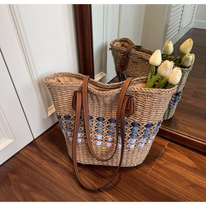 Détail de sac cabas en paille avec motif de losanges dégradés et anses en cuir marron