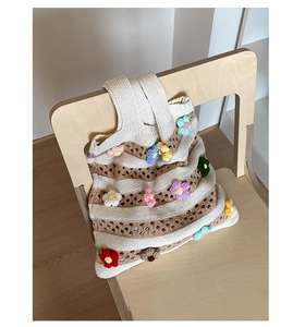 Détail du sac cabas au crochet à rayures avec fleurs 3D colorées sur une chaise en bois