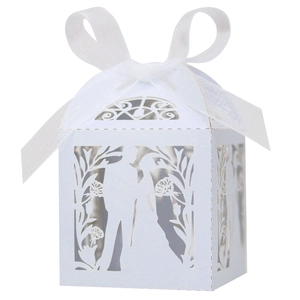 Detailed macro view of laser-cut wedding favors box with white ribbon and floral silhouette