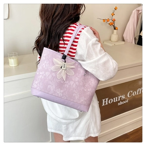 Detailed embroidery on light purple tote bag with lavender leather strap and floral charm