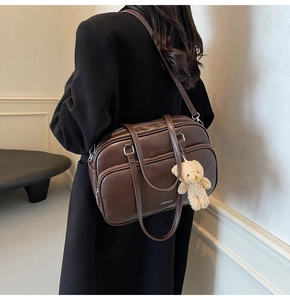 Model wearing dark brown vintage leather boston bag with plush bear charm detail