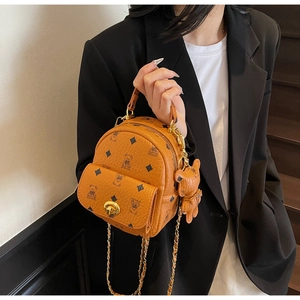 Detailansicht eines braunen Mini-Rucksacks mit Goldkette und Bären-Anhänger-Detail