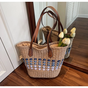 Détail d'un sac cabas en paille tissé avec motifs ajourés et poignées en cuir