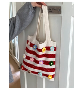 Détail du cabas en tricot rayé rouge et blanc avec appliques florales au crochet