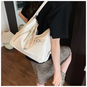 Detail of white crocodile embossed hobo bag featuring silver zipper and woven pendant