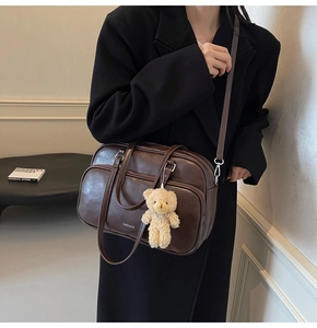 Detail of vintage dark brown pillow bag with bear pendant and white logo lettering