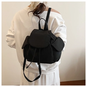 Rear view of model wearing a black nylon drawstring backpack with side flap pockets