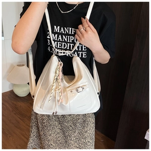 Detail view of white croc-embossed tote bag with silver zippers and colorful charm