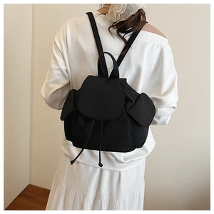 Detail view of the black canvas backpack featuring a drawstring closure and a minimalist flap