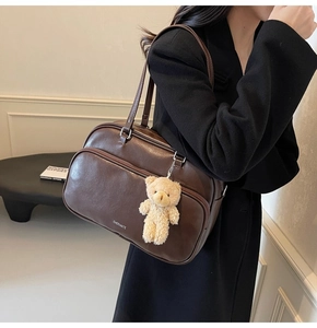 Detail of vintage dark brown shoulder bag with zipper pocket and cute plush bear charm