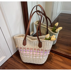 Détail d'un sac cabas en paille tissé à la main avec rayures et lanières en cuir brun