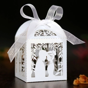 Detail of white laser-cut wedding favor box featuring bride and groom silhouette and ribbon