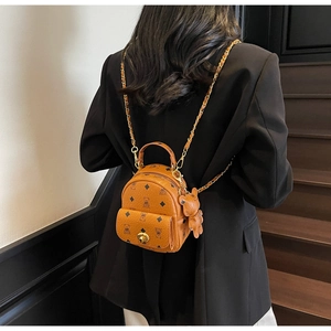 Detailansicht eines braunen Mini-Rucksacks mit Bärenmuster und Metallkette am Modell