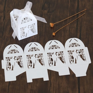Detail of laser-cut white wedding favor box with ribbon and flat-pack assembly view