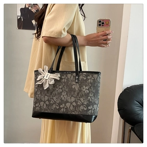 Detail of grey floral jacquard tote bag with leather base and white flower charm pendant