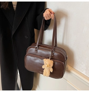 Detail of vintage dark brown Boston bag with plush bear charm and clear leather texture
