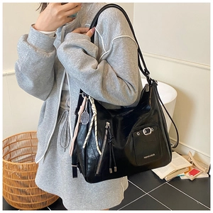 Detailed shot of high-shine black crocodile pattern tote bag with creative charms and strap