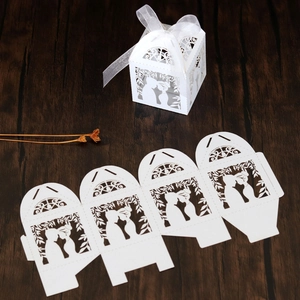 Detail of laser-cut white wedding favor box showing couple silhouette and ribbon bow