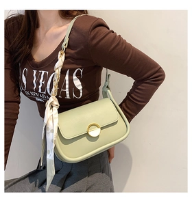 Détail du sac selle vert menthe avec boucle métallique et foulard décoratif en soie