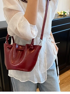 Chic burgundy bucket bag with knotted handle and shiny leather finish for women